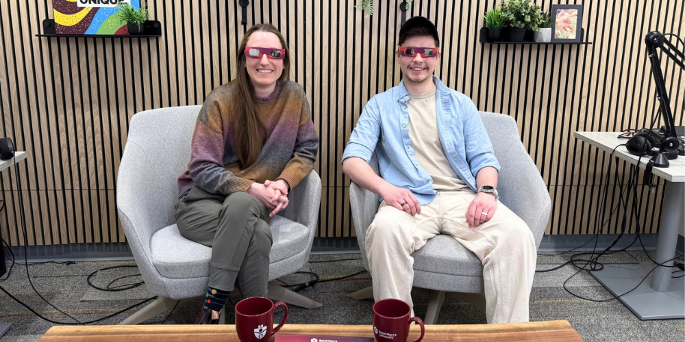 Astronomy Tech Tiffany and student sit together in the podcast studio wearing eclipse glasses